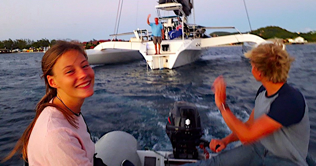Crew members in a tender leaving the Rapido 60 trimaran Ineffable at anchor.
