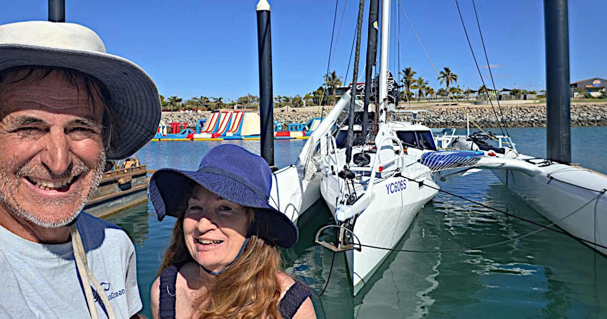 Alan Noble and Merri beside Rapido 40 Lightning at Port Hedland's Spoilbank Marina, showing the starboard float folded inward to reduce the yacht's beam.