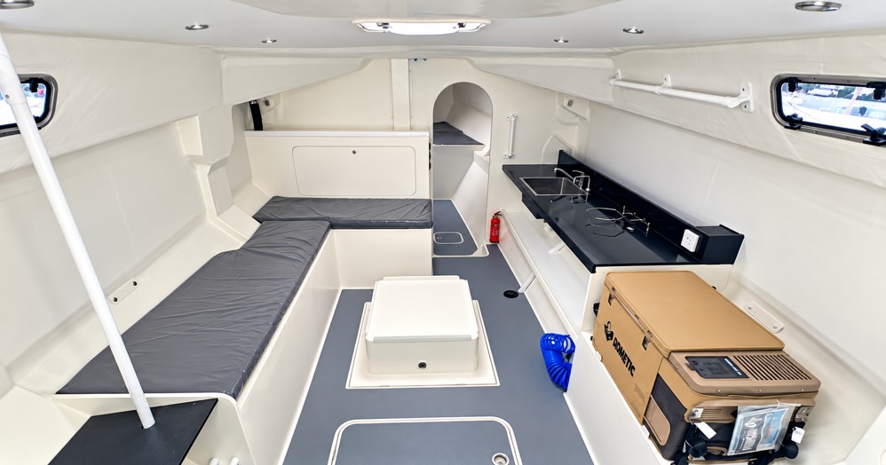 Rapido 40 Racer saloon interior with lowered cabin sole, settee seating, compact galley and lightweight racing-focused fitout.