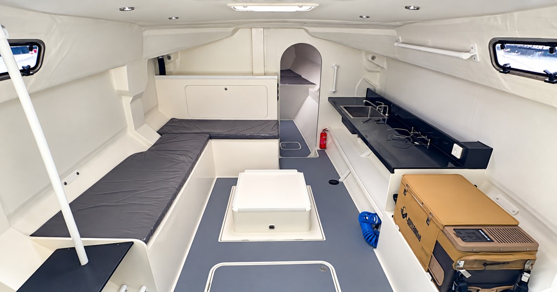 Rapido 40 Racer interior showing lightweight bench seating, compact galley, navigation and storage areas, and access to the forward cabin.