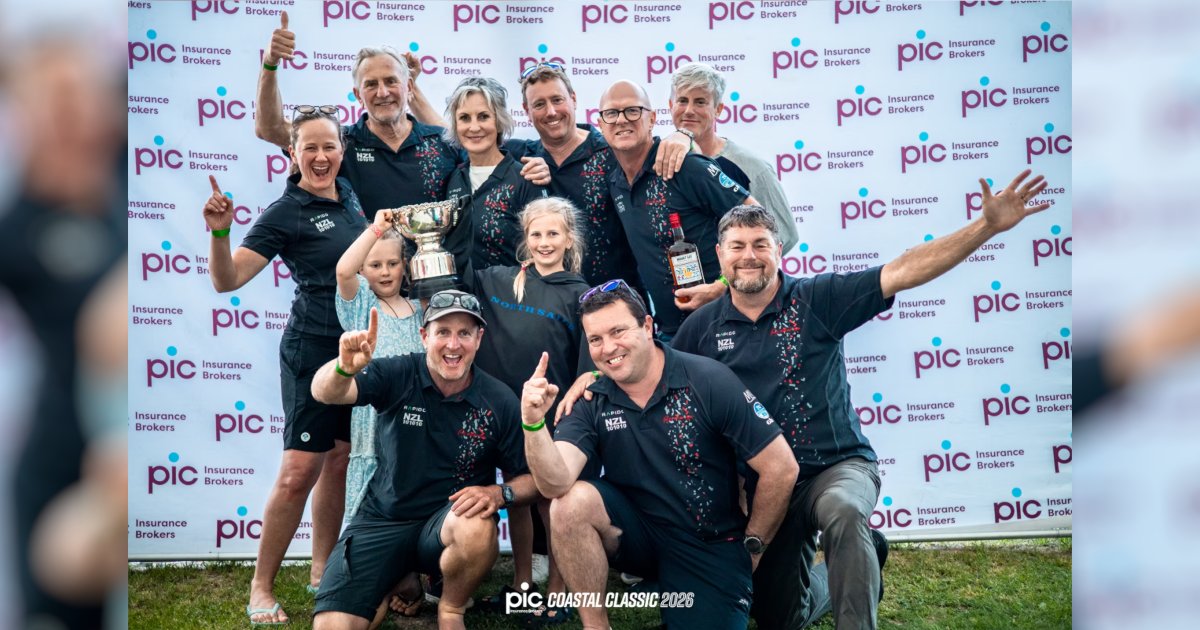 Team Romanza crew celebrating their Multihull Handicap victory at the 2026 PIC Coastal Classic, holding their trophy at the prizegiving.